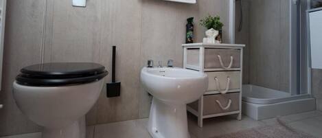 A bathroom with a toilet, bidet, and a small cabinet with drawers.
