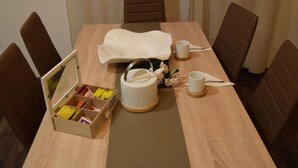 A dining table with a white placemat, a white napkin holder, and a small vase with flowers. There are brown chairs around the table.