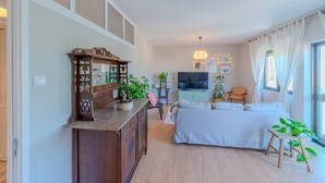 A living room with a sofa, a wooden cabinet, a TV, and a plant. - VIVA Spacious 3 bedroom apartment (Porto)