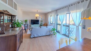 A modern living room with a sofa, TV, and dining area. - VIVA Spacious 3 bedroom apartment (Porto)