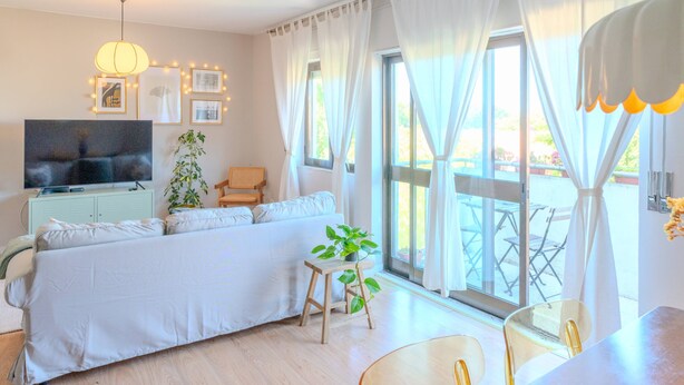 A modern bedroom with a large bed, a TV, a small table with a plant, and a balcony with outdoor furniture. - VIVA Spacious 3 bedroom apartment (Porto)