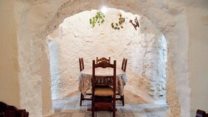 Un coin repas avec une table et des chaises, un mur blanc à la texture intéressante et une petite plante accrochée au mur.