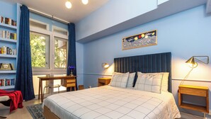Een slaapkamer met een groot bed, een bureau, een boekenkast en een raam met gordijnen.