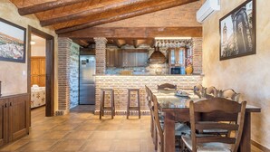 A rustic kitchen with exposed brick walls, wooden beams, and a central island with stools.