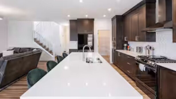 A modern kitchen with a central island, dark wooden cabinets, and a stainless steel stove.