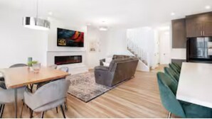 A modern living room with a dining area, a sofa, and a staircase leading to another level.
