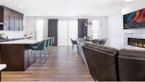 A modern kitchen with a central island, bar stools, and a dining area with a sofa.