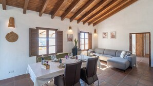 Un comedor con una mesa dispuesta para cuatro personas, un sofá y techo de madera.