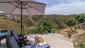 Una veranda con posti a sedere all'aperto, un tavolo e un ombrellone grande.