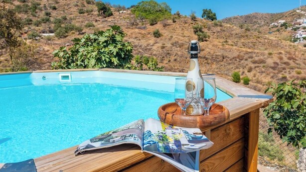 Solarium in legno con vasca idromassaggio, un vassoio con bicchieri e una rivista.
