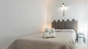 Un letto rifatto con una coperta a fantasia e due asciugamani con un logo.