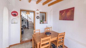 Zona pranzo con tavolo e sedie in legno, una sveglia e un quadro appeso al muro.