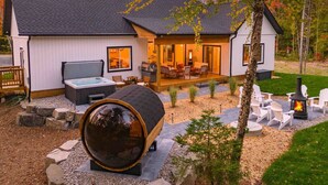 A modern house with a hot tub, outdoor seating, and a fire pit.