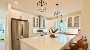 A modern kitchen with white cabinetry, stainless steel appliances, and a large island with seating.