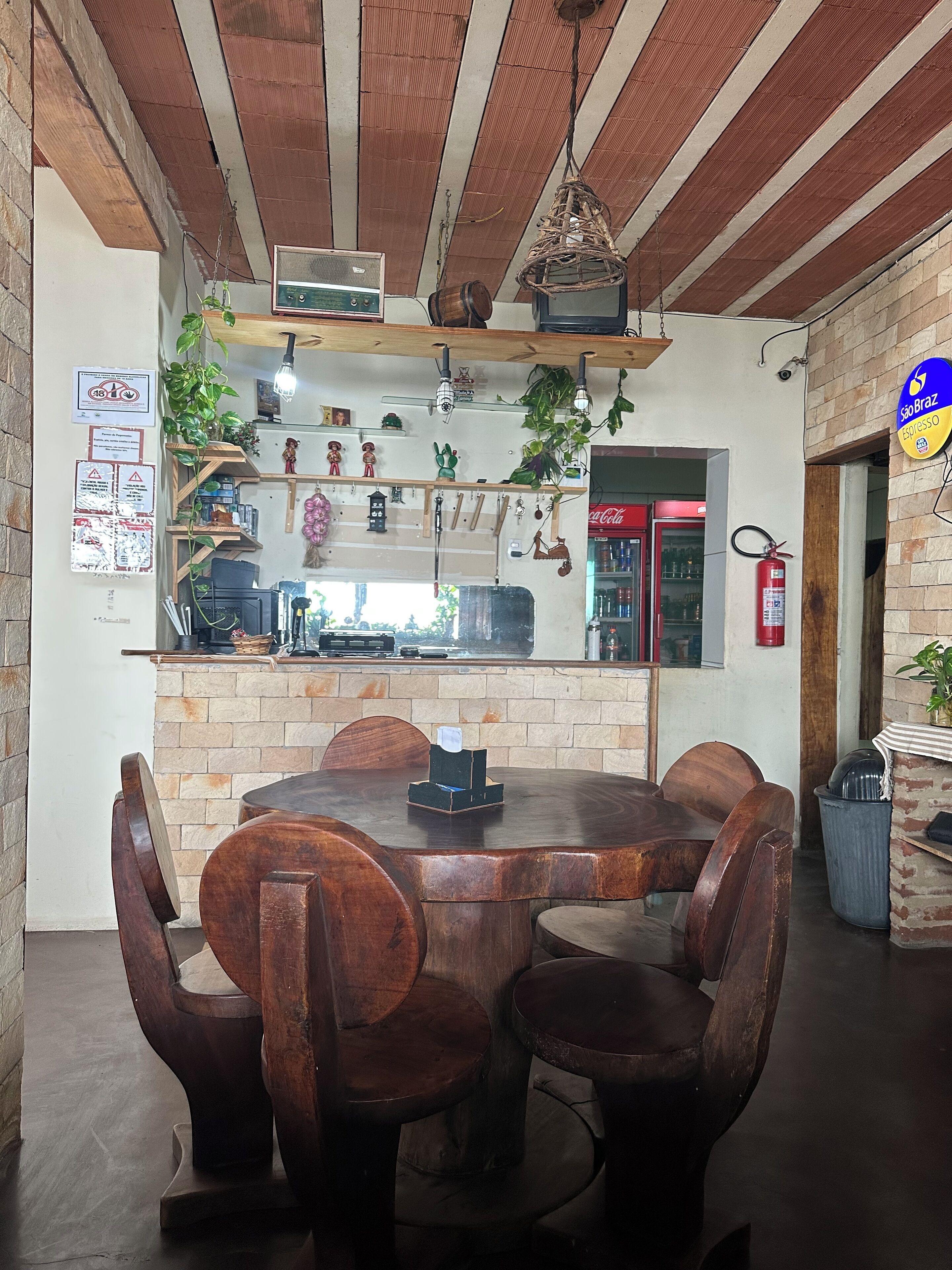 Um café acolhedor com uma mesa e cadeiras de madeira redondas, uma parede de tijolos e um lustre.