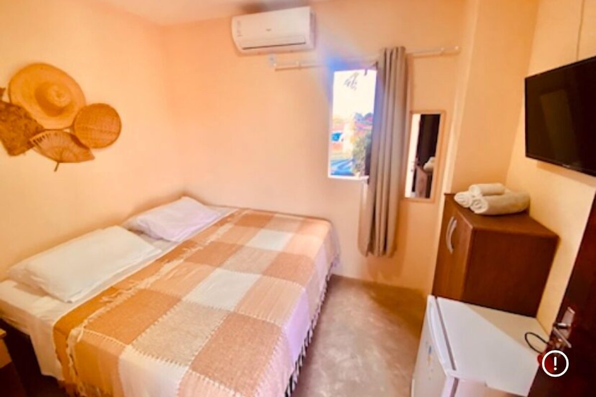 Una habitación de hotel con cama, televisión, escritorio y aire acondicionado.
