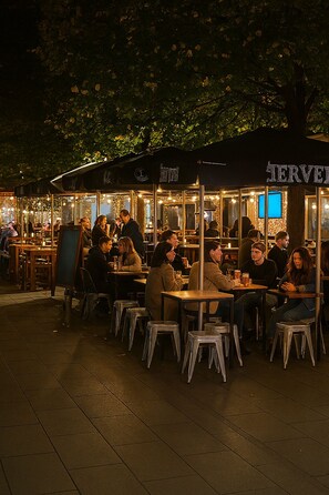 An outdoor café with tables and chairs under a canopy, surrounded by trees. - Raffa in Pigneto   (Roma)