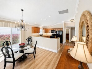 Una cocina moderna con armarios de madera, una isla central y un comedor con candelabro.
