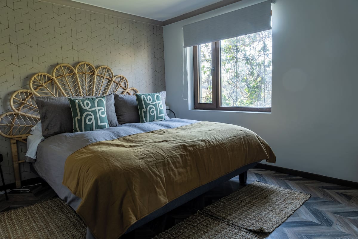 A bedroom with a bed, a window, and a patterned wall.