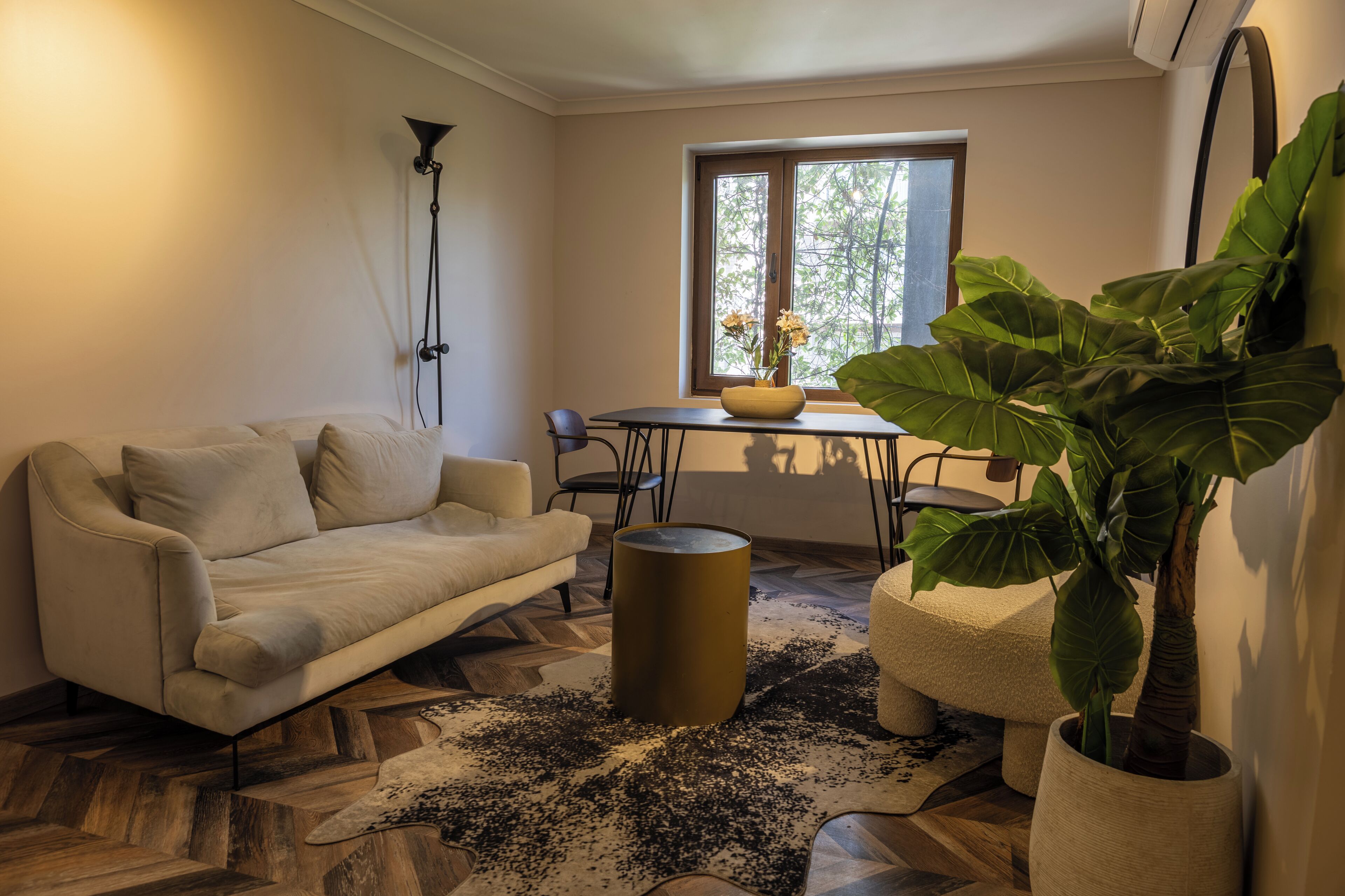 Ein modernes Wohnzimmer mit einer Couch, einem Couchtisch und einer großen Pflanze.