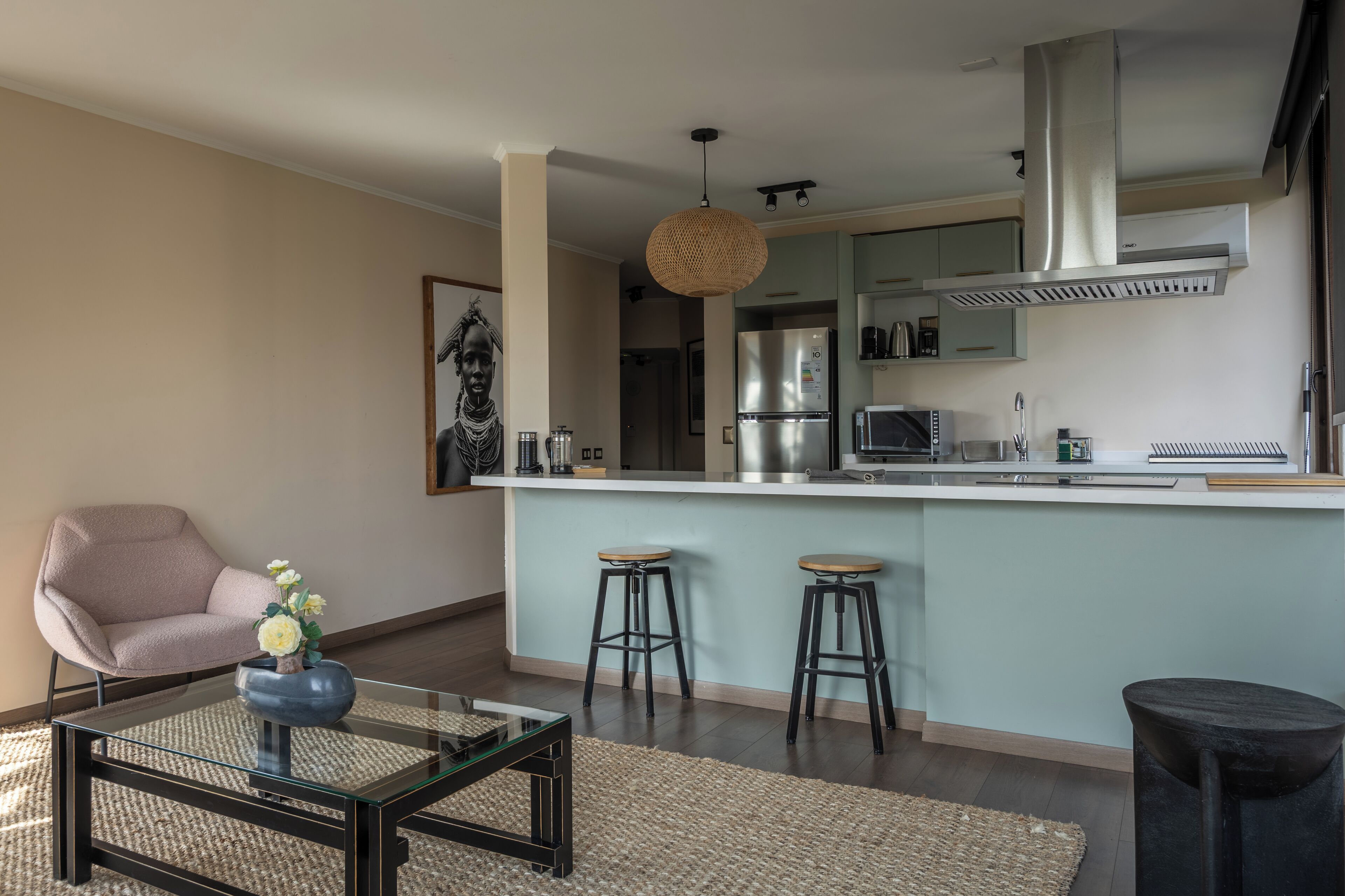 A modern kitchen with a central island, bar stools, and a hanging light fixture.