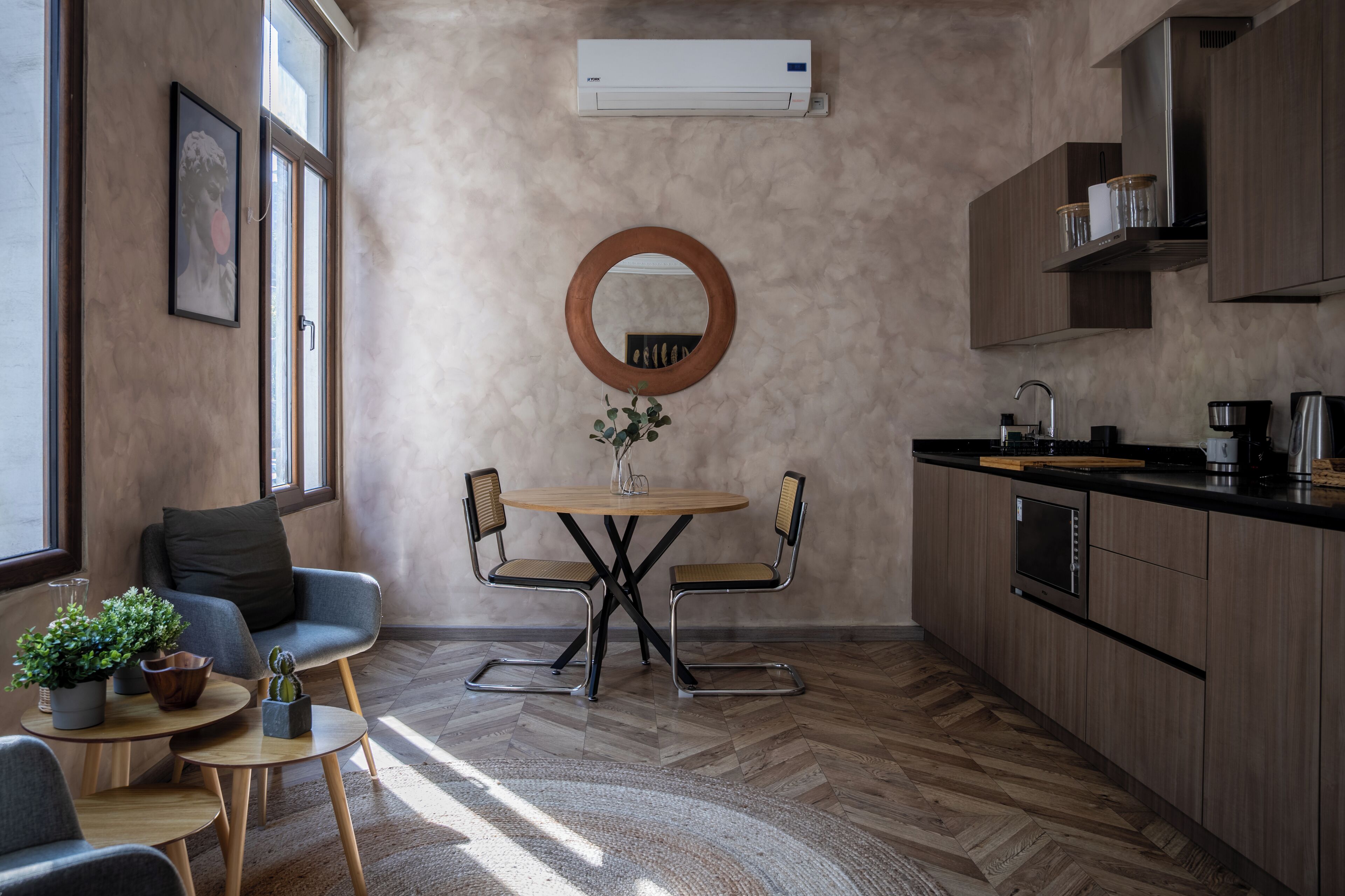 Una cocina moderna con armarios de madera, un espejo redondo y un comedor con mesa y sillas.