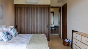 Ein Schlafzimmer mit Bett, einem Holzschrank, einem Badezimmer mit Waschbecken und einem Spiegel.