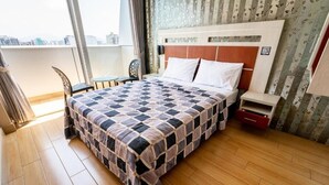 A hotel room with a large bed, a small table, a chair, and a view of the city through large windows. - HOTEL QUADRUM (Lima)