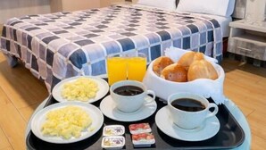 A hotel room with a bed, breakfast tray, and a bedside phone. - HOTEL QUADRUM (Lima)