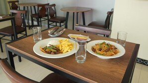 A dining table with two plates of food, a glass of water, and a small bowl of fries. - HOTEL QUADRUM (Lima)