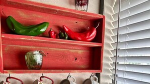 Ett kök med en röd hylla där det står paprika och en korg med koppar.