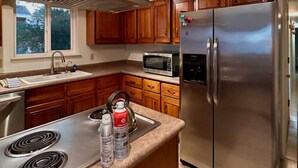 Una cocina moderna con electrodomésticos de acero inoxidable, armarios de madera y una isla grande con hervidor y extintor.