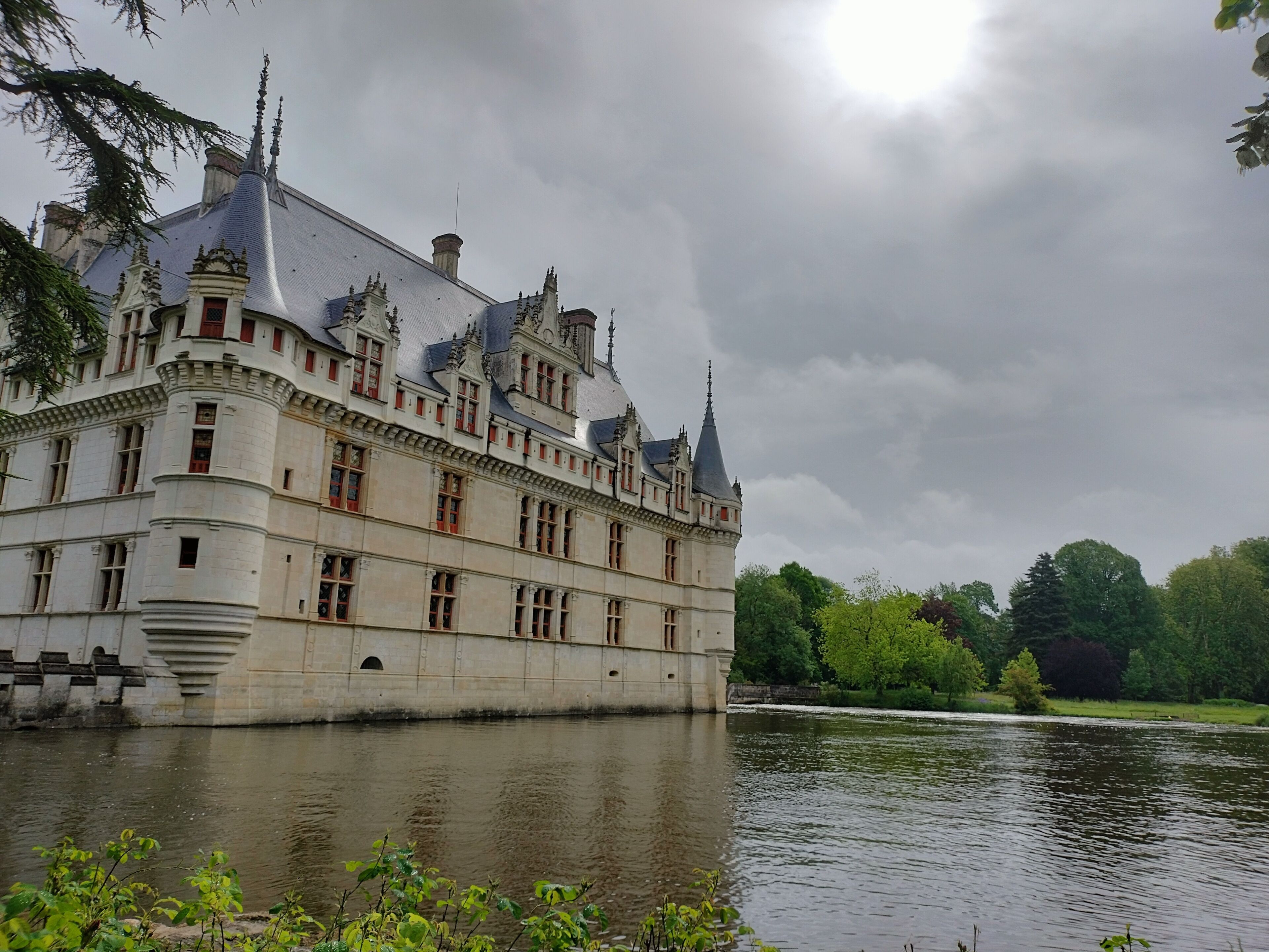 A large, historic building with multiple towers and a river in the foreground.