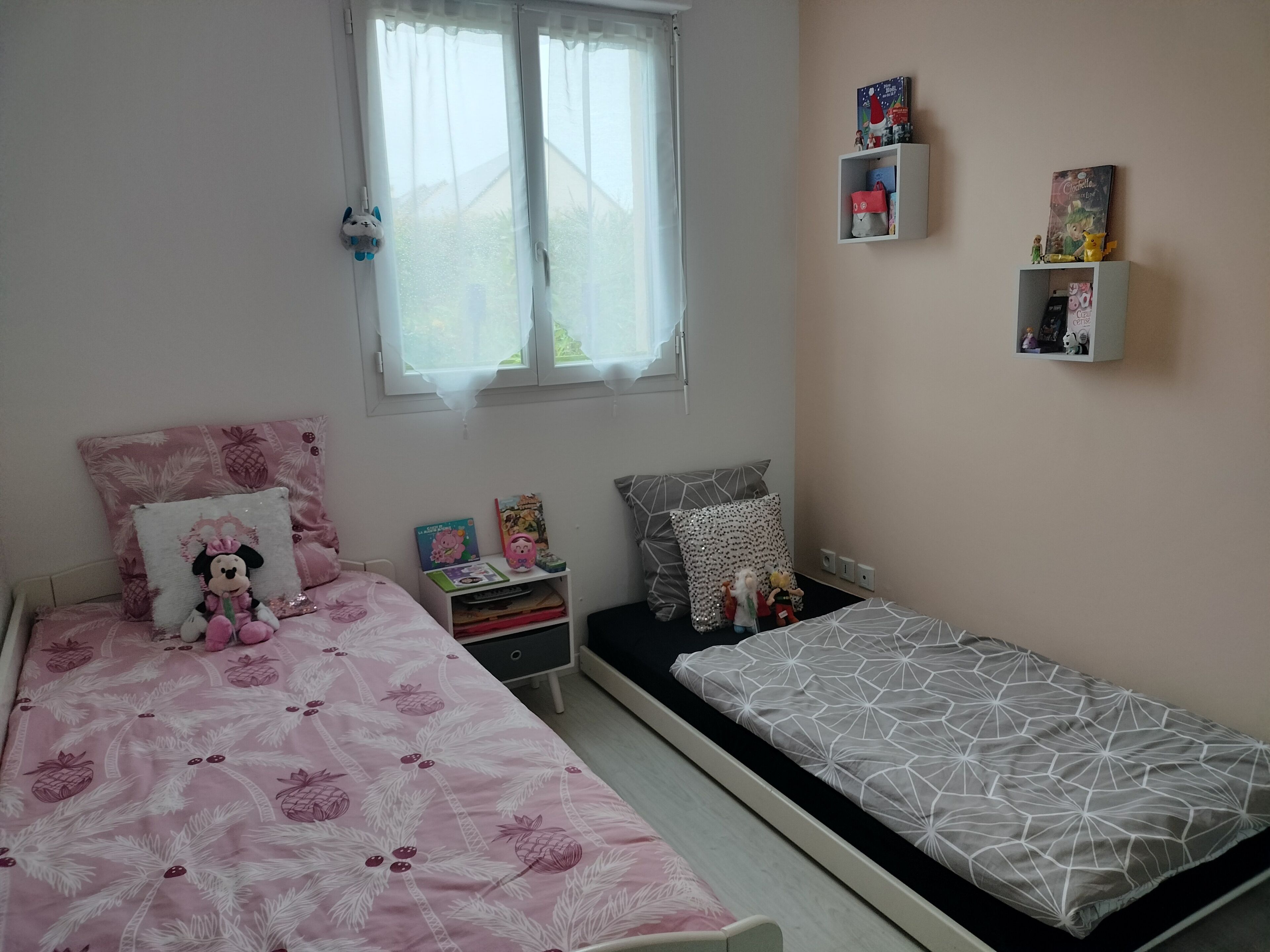 A bedroom with a bed, a nightstand, a dresser, a window, and a wall shelf.