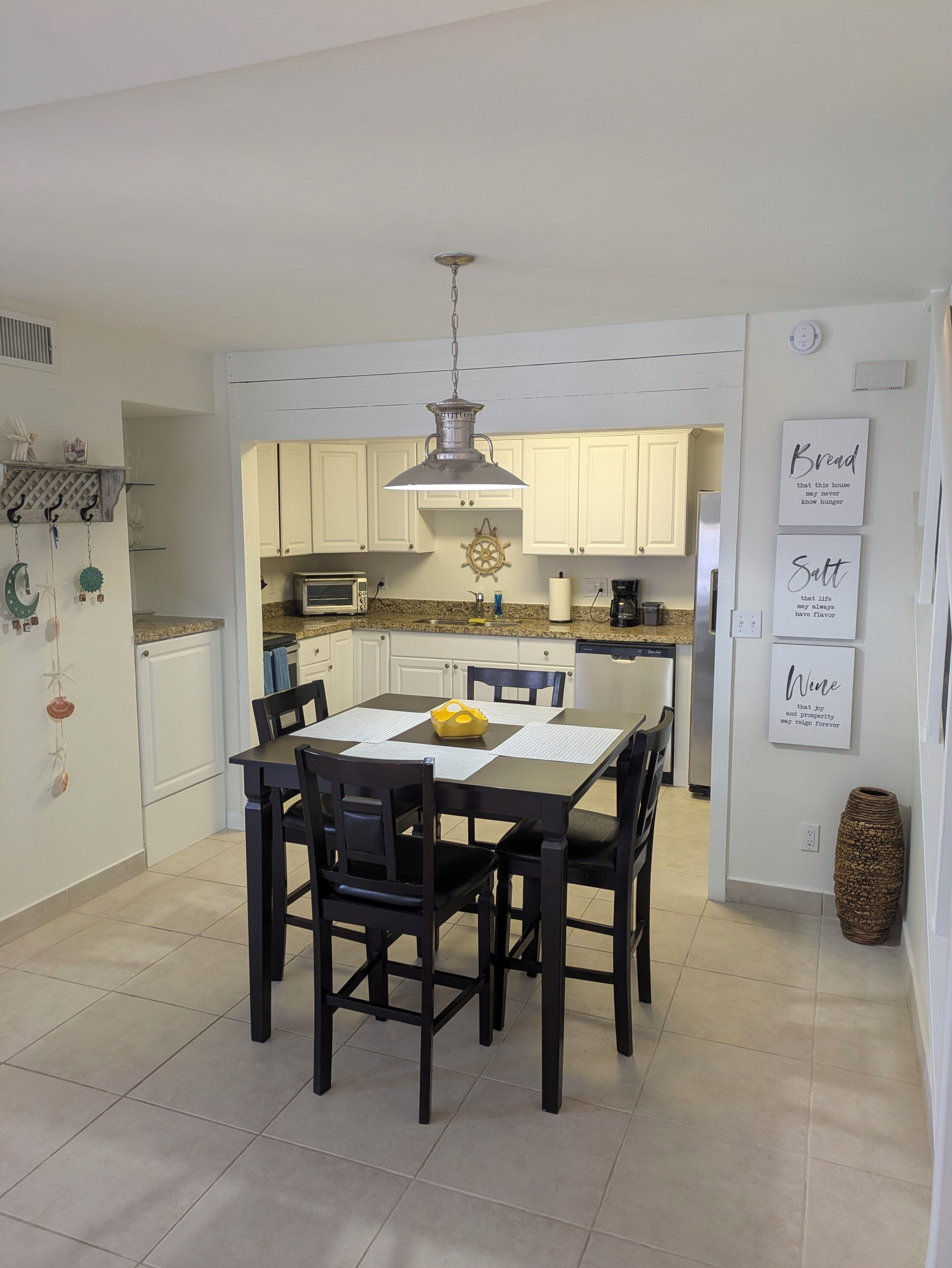 A modern kitchen with white cabinets, a central island, and a dining area with black chairs.