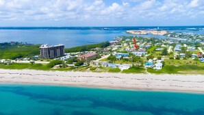 Oversigtsbillede af en kystresort med strand, en stor hotelbygning og en lysthavn.