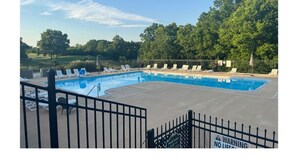 A swimming pool with lounge chairs and a fenced area.