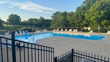 A swimming pool with lounge chairs and a fenced area.