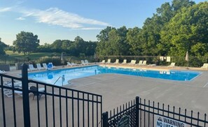 A swimming pool with lounge chairs and a fenced area.