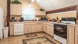 A kitchen with wooden cabinets, a white stove, a microwave, and a dishwasher.