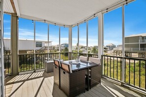 A covered outdoor area with a table and chairs, large windows, and a view of other buildings. - Stunning 4 BR Pet Friendly House w\ Beach Access (Gulf Shores)