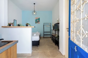 A modern kitchen with a wooden countertop, a hanging light fixture, and a blue wall with a poster.