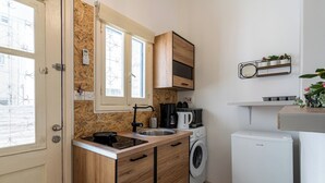 A compact kitchen with wooden cabinets, a built-in washing machine, and a small refrigerator. - Simba Studio in Larnaca & Terrace (Larnaca)