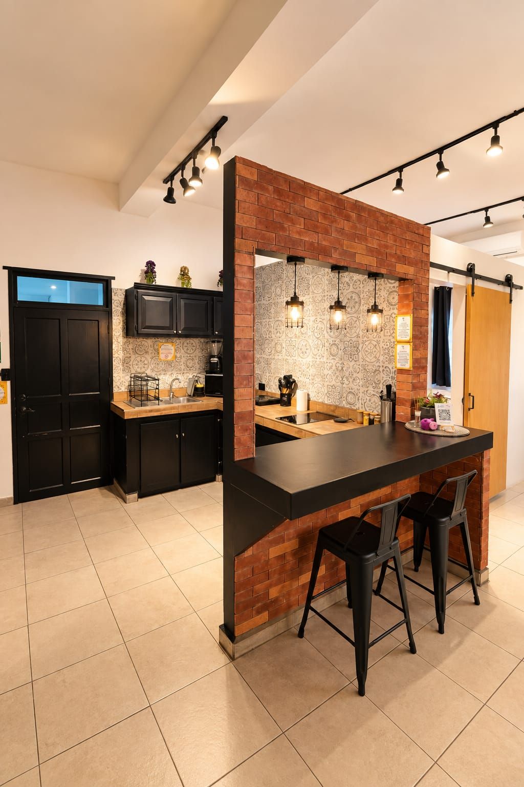 A modern kitchen with a central island, black bar stools, and pendant lighting.
