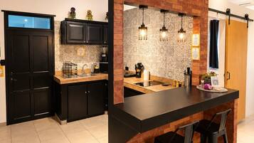 A modern kitchen with a central island, black bar stools, and pendant lighting.