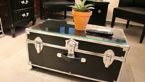 Une valise noire avec un dessus en verre, posée sur un sol carrelé.