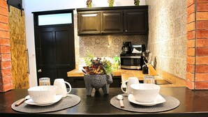 Une cuisine avec des meubles de couleur sombre, un four à micro-ondes et une machine à café. On peut voir une plante dans un pot en pierre posé sur le comptoir.