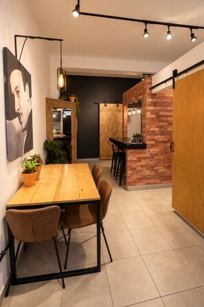 Un espace repas moderne avec une table en bois, des chaises et un coin bar agrémenté d’un mur en briques.