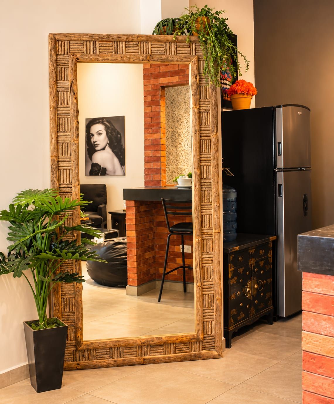 A kitchen with a black refrigerator, a wooden cabinet, and a dining area with a chair and table.