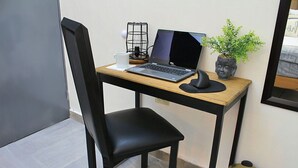 Een kleine werkplek met een laptop, een kopje, een plant en een prullenbak.